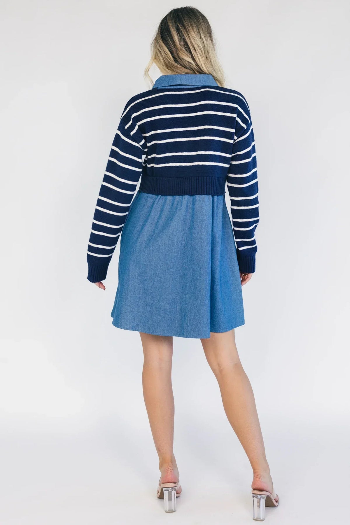 Model wearing a navy and ivory striped sweater dress with a collared neckline, functional button-front detail, long sleeves, and an elastic waist.