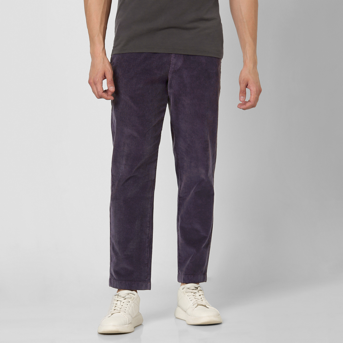 A person wears dark grey tee, white sneakers, and Corduroy Easy Pant in soft purple cotton, standing against a light background. Image cropped at the shoulders—perfect style inspiration for your fall and winter wardrobe.