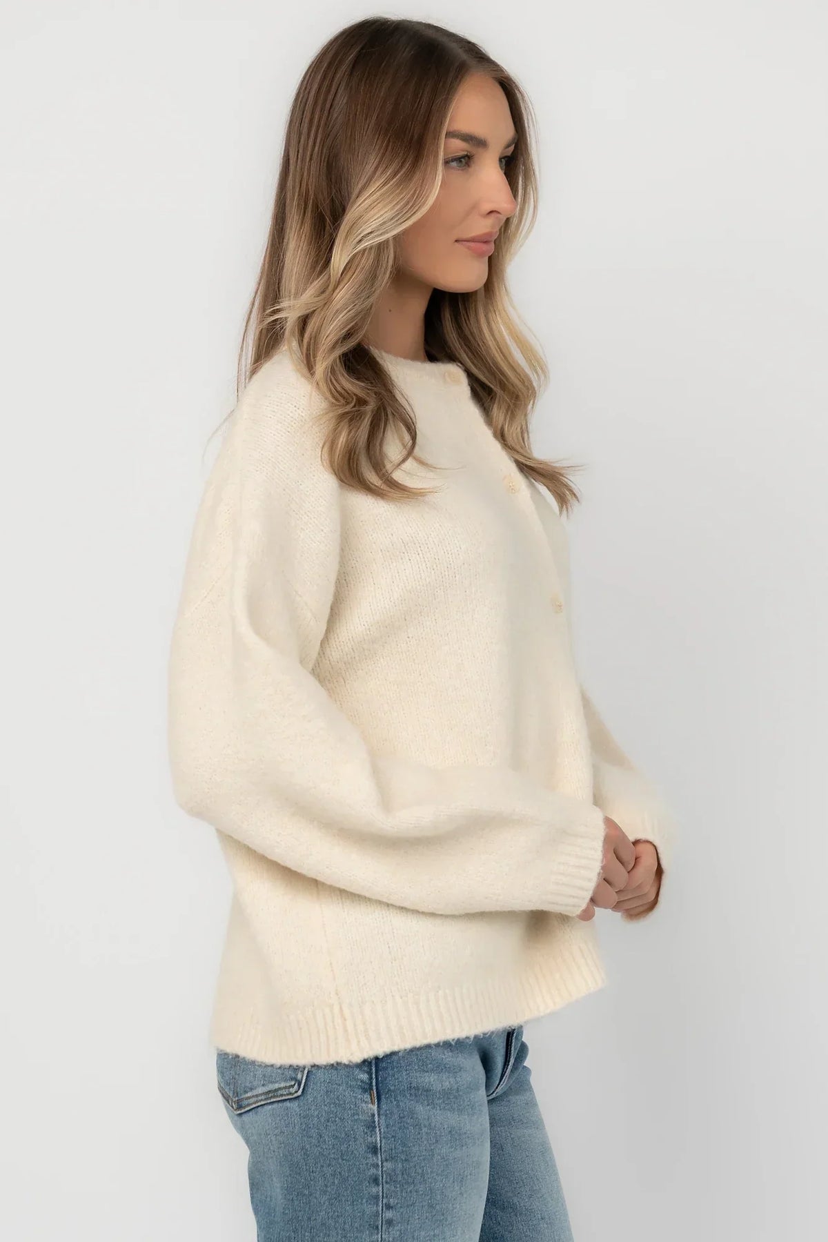 Cream fuzzy knit cardigan with a round neckline, button-front closure, long sleeves, dropped shoulders, and a relaxed fit.