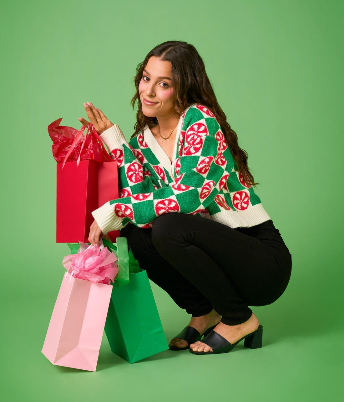 Woman wearing a green and red patterned sweater with a plain background