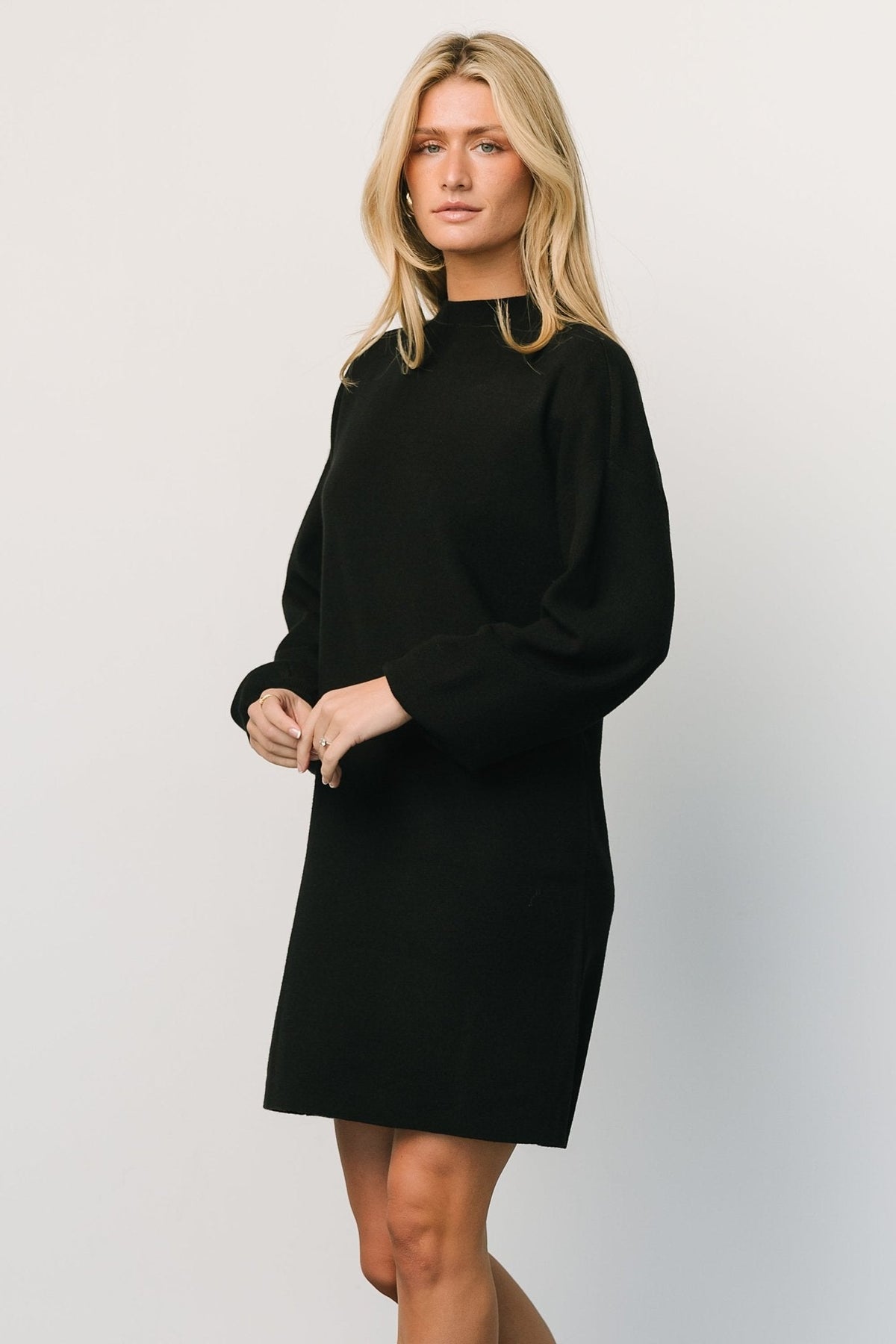 Detail view of the sweater dress hem and side seam, showing short length and clean finishing suitable for boots or layered looks.